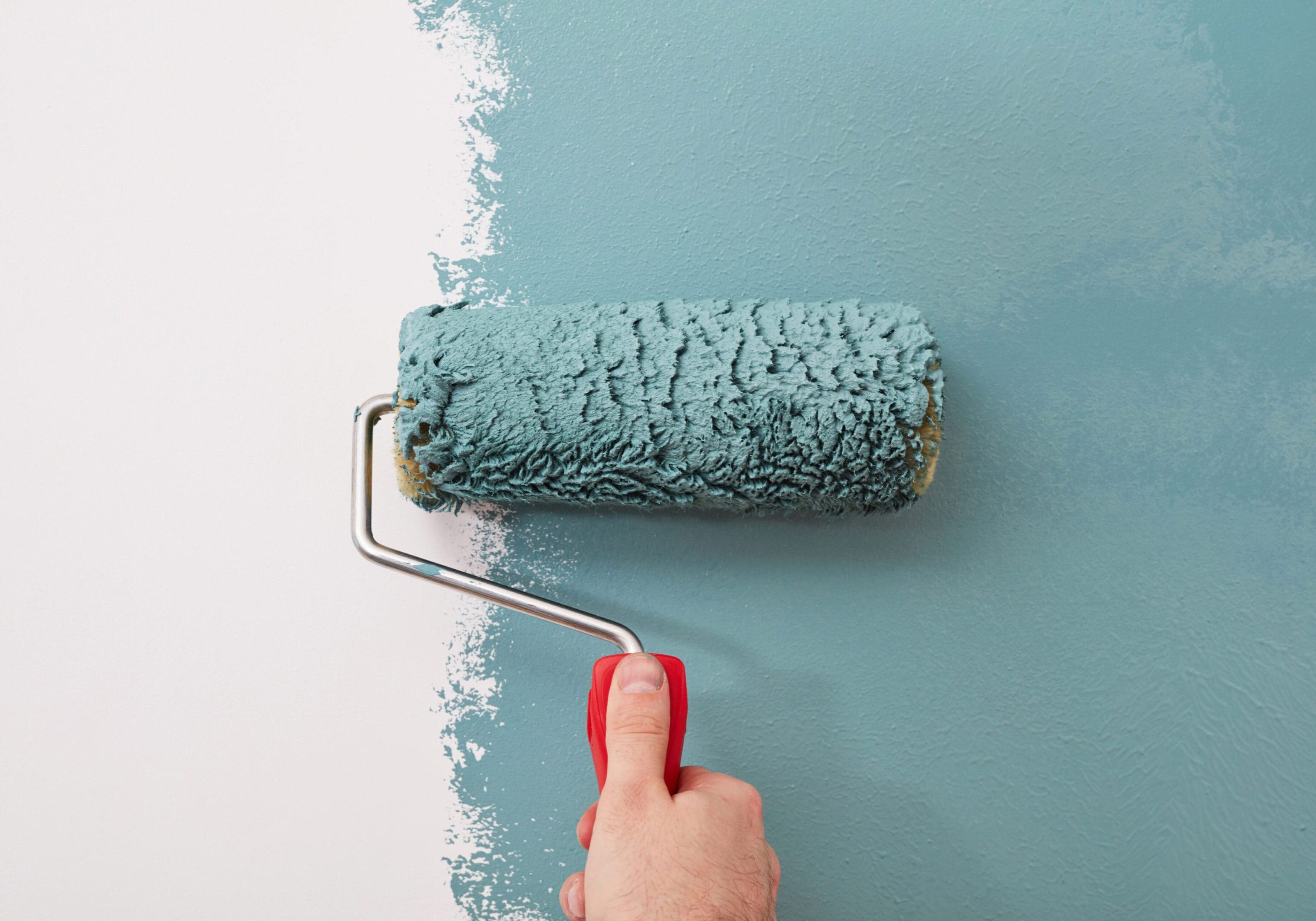 Male hand painting wall with paint roller